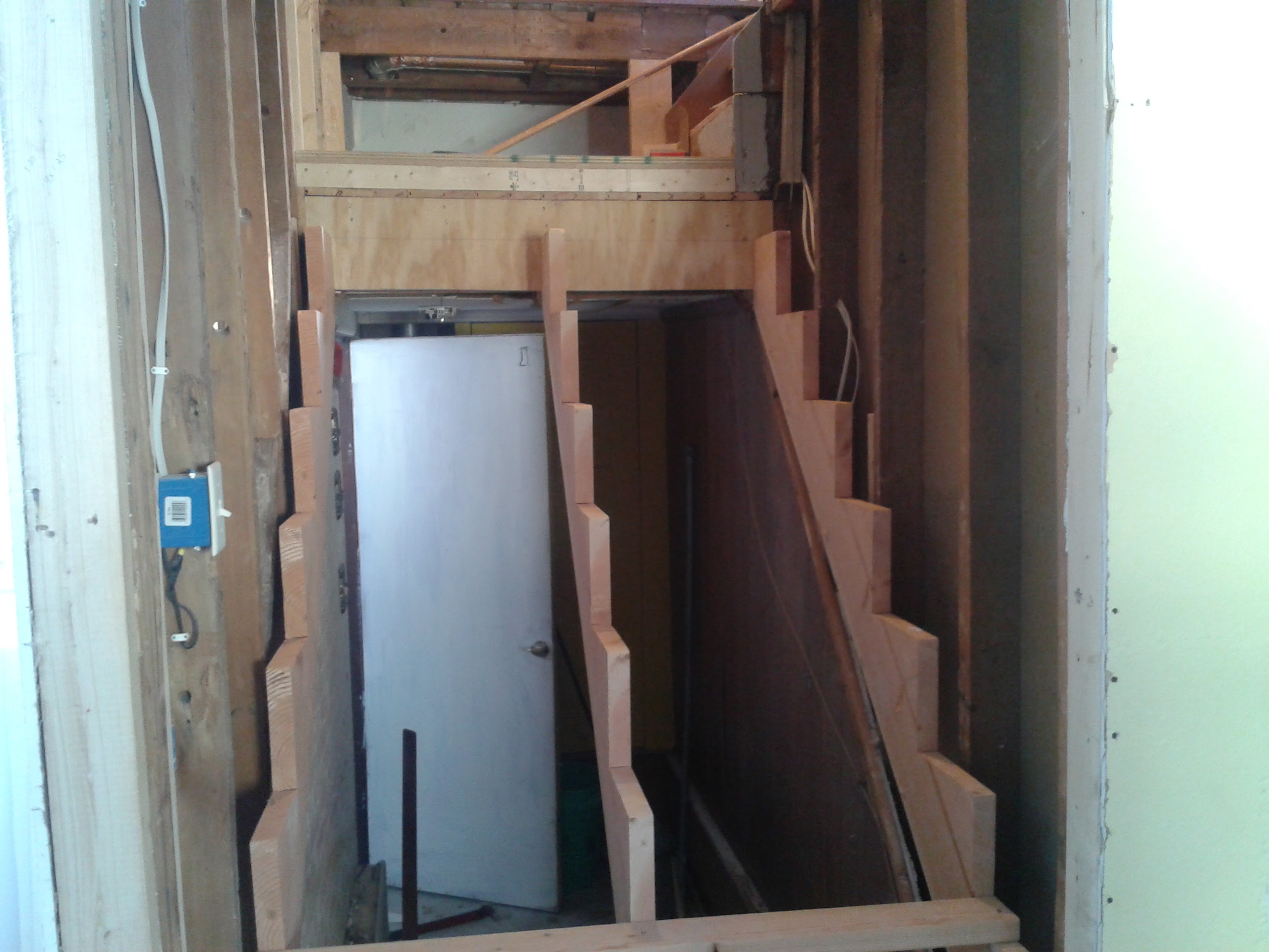 Staircase fully demoed with new stringers exposed and framing visible