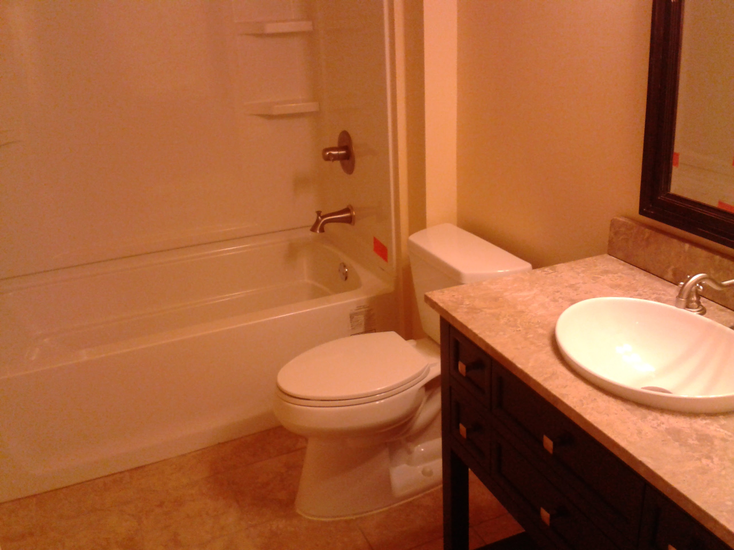 Completed bathroom with tub, toilet, vanity, and tile floor