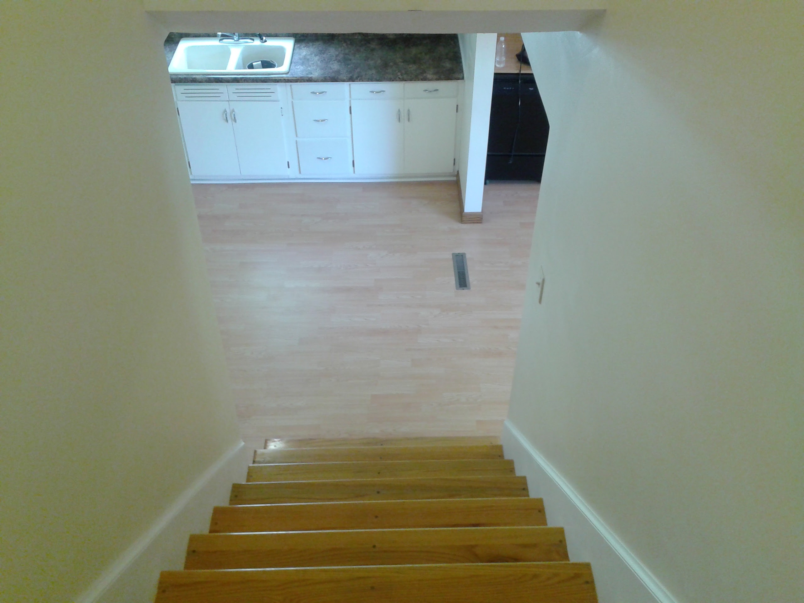 View from top of completed staircase looking down to finished kitchen and laminate flooring