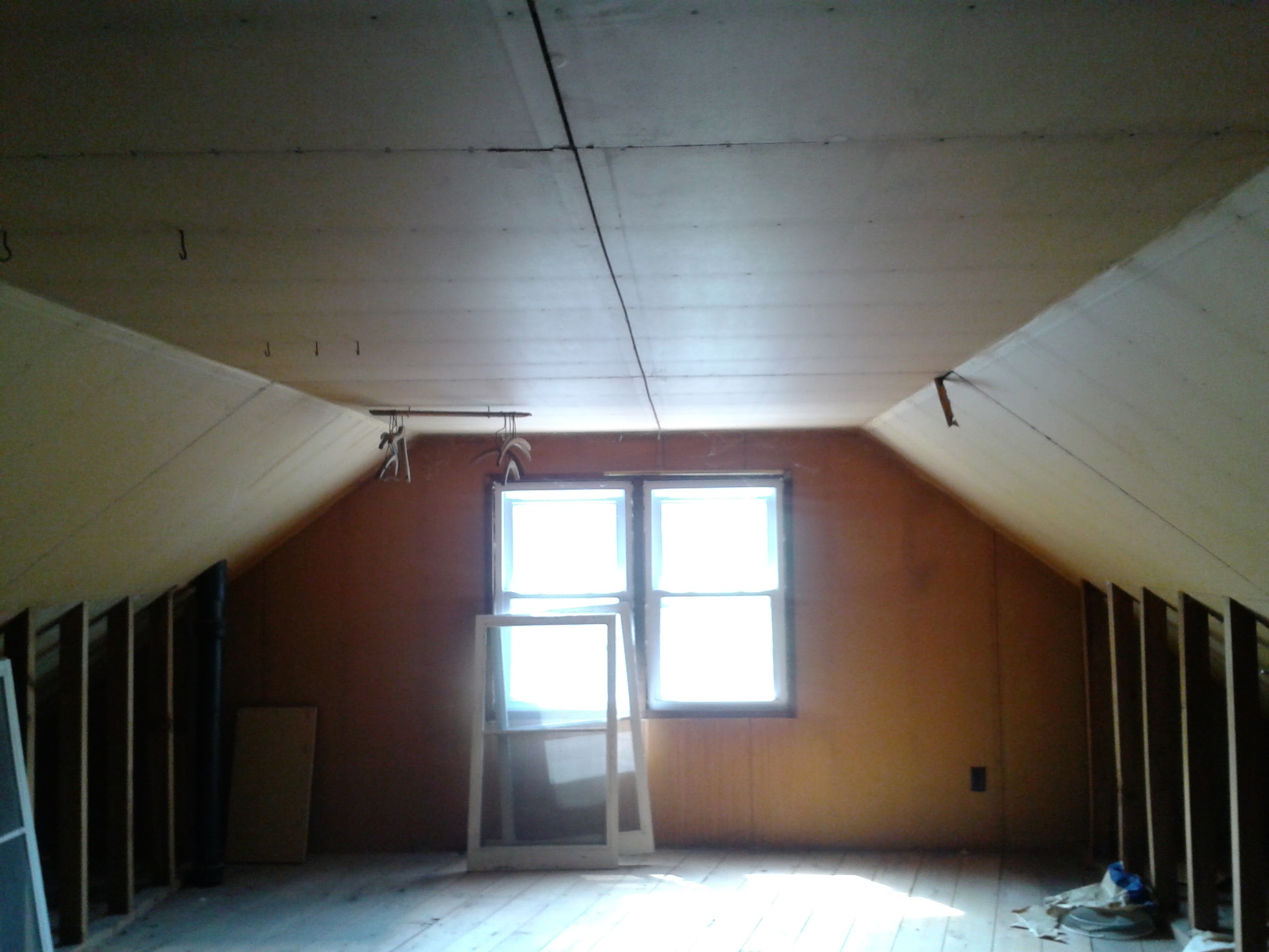 Attic before remodel — open space with sloped ceiling and windows