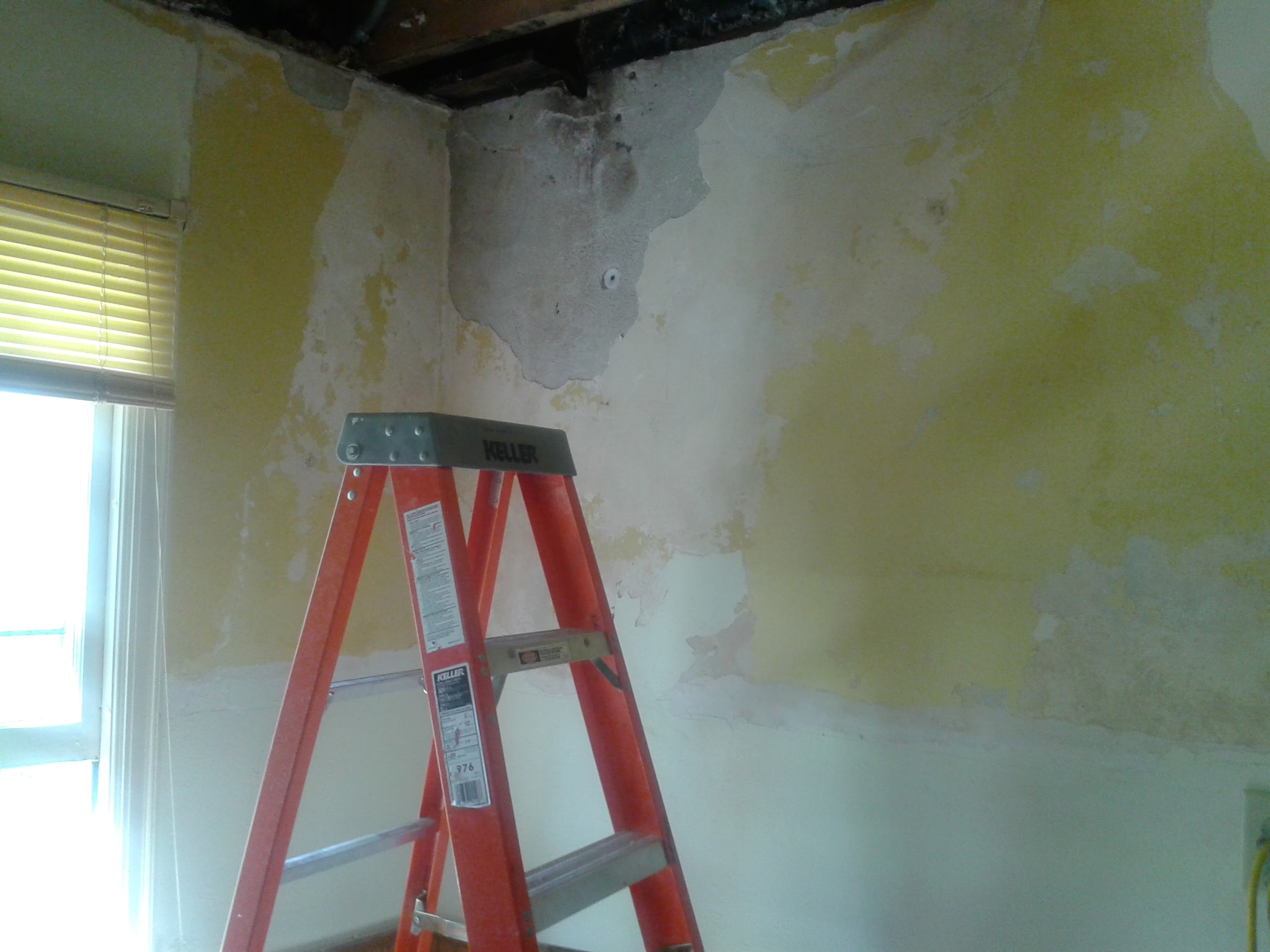 Water damaged walls and ceiling with peeling paint before repair