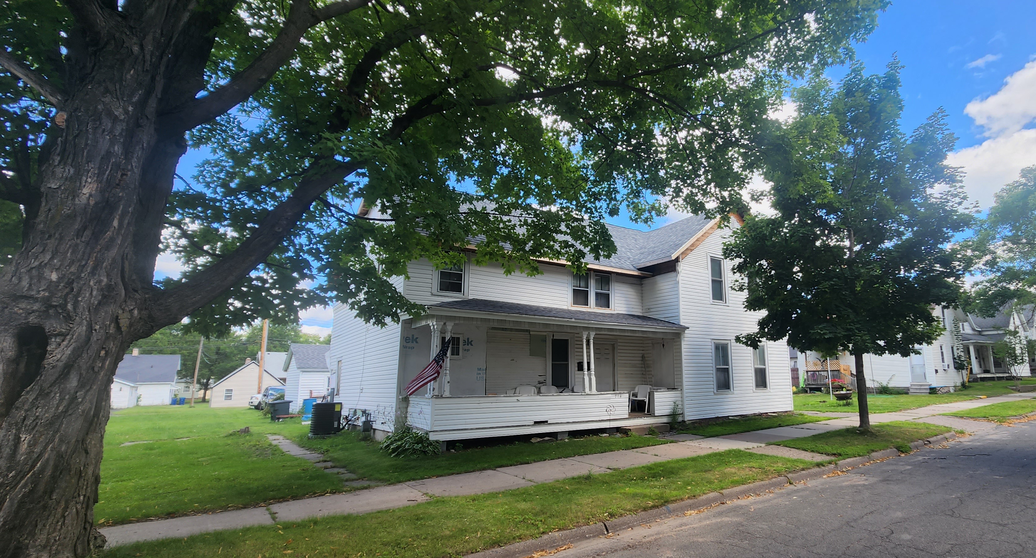 Two-story home with new white vinyl siding and covered front porch mid-renovation