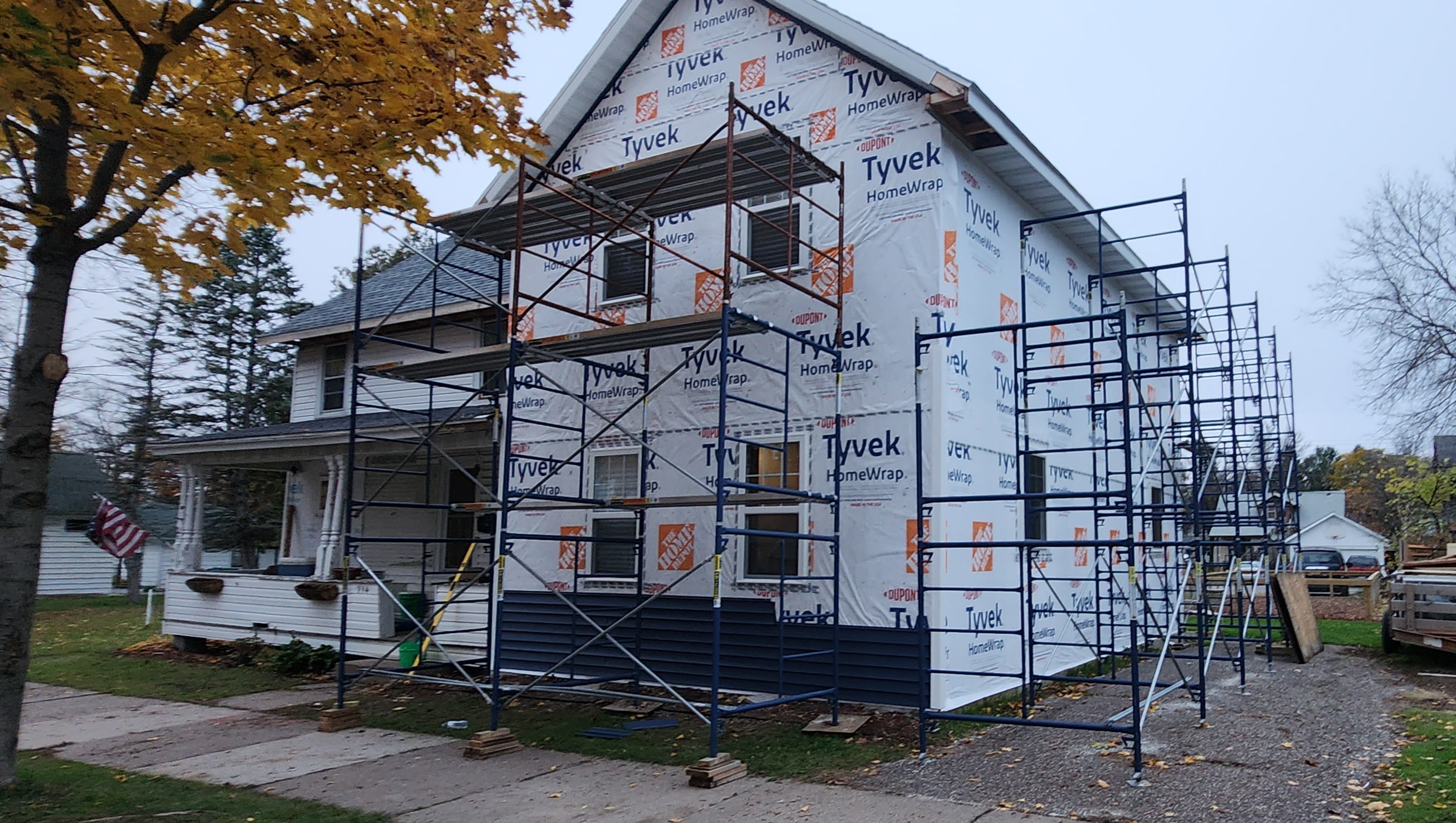 Full scaffolding erected on front of two-story home, Tyvek wrap complete