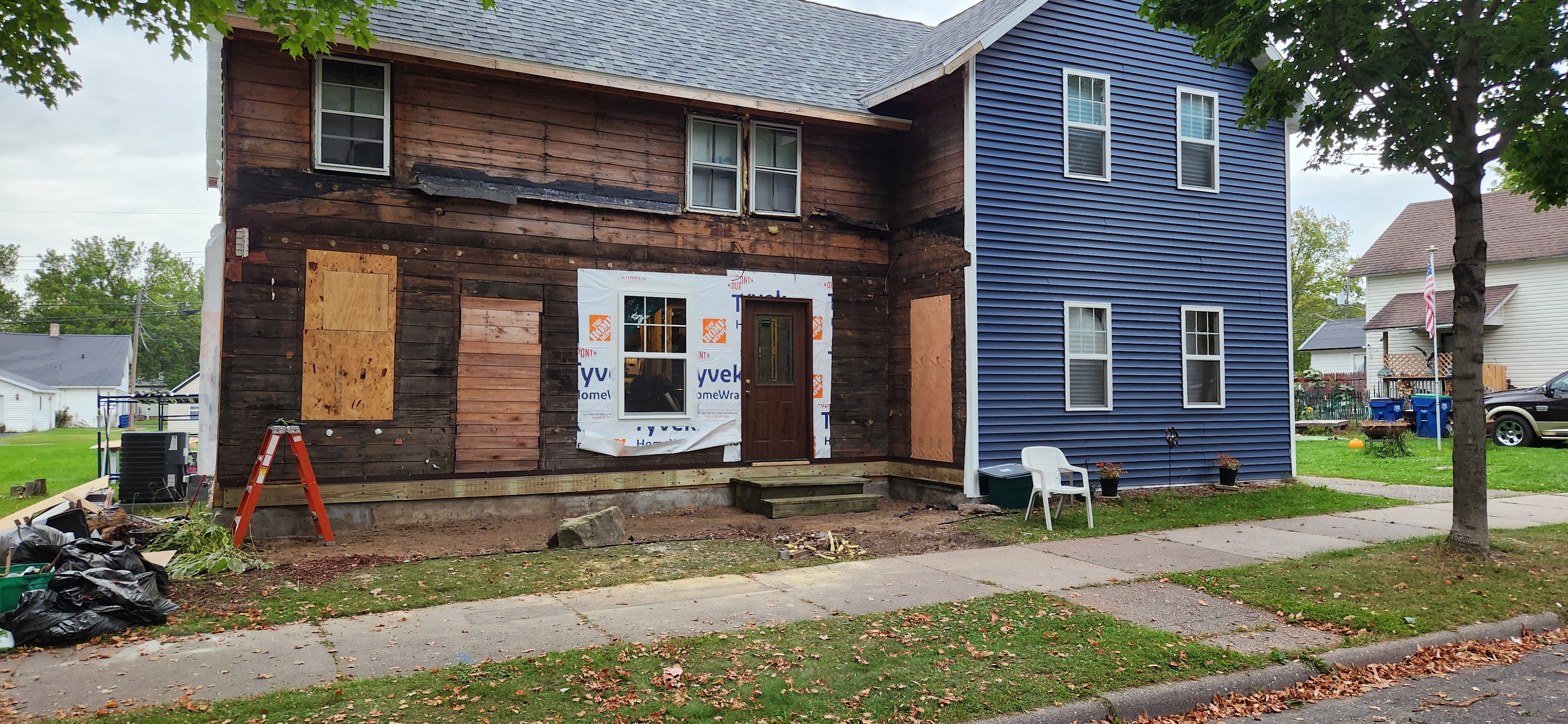 Exterior remodel in progress — siding removed, Tyvek wrap installed