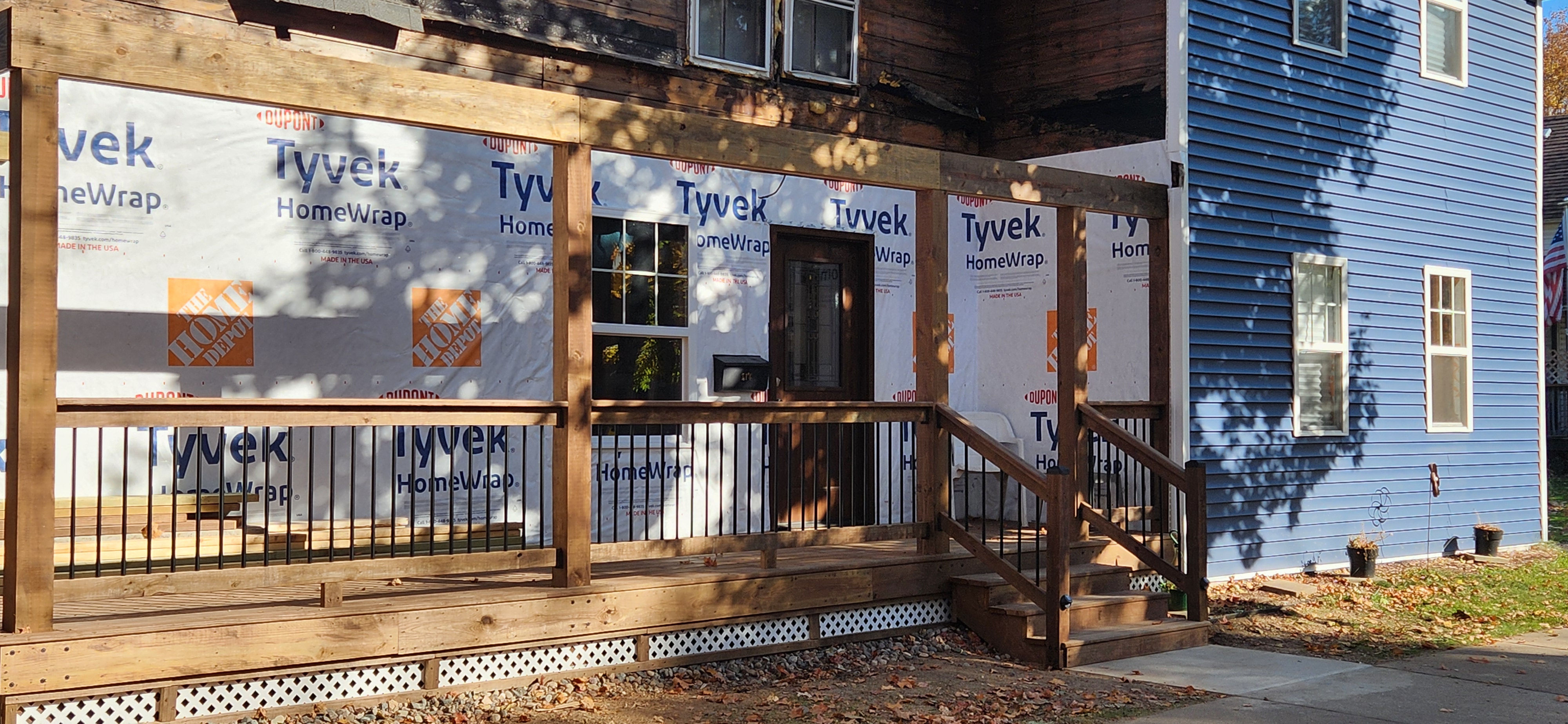 Porch structure with deck boards, railing, and stairs taking shape