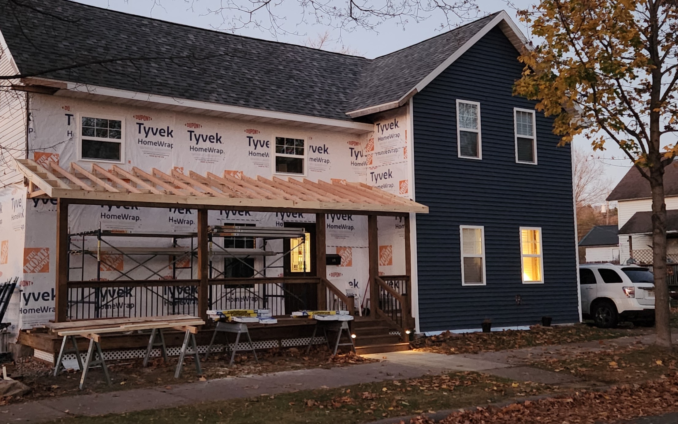 Porch roof rafters framed at dusk with new blue siding visible