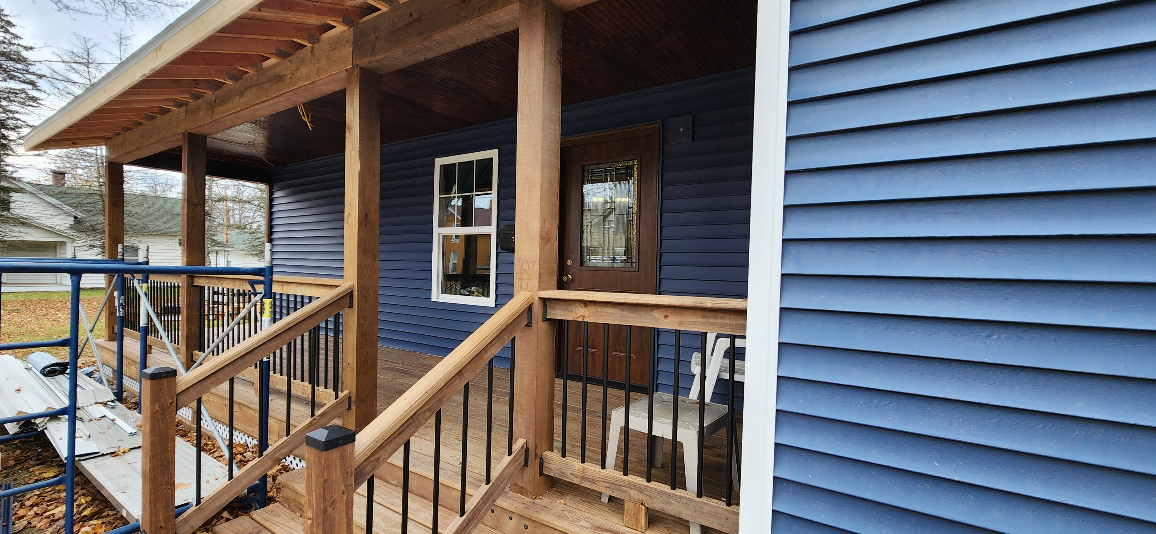 Completed covered front porch with cedar posts, railing, and new entry door
