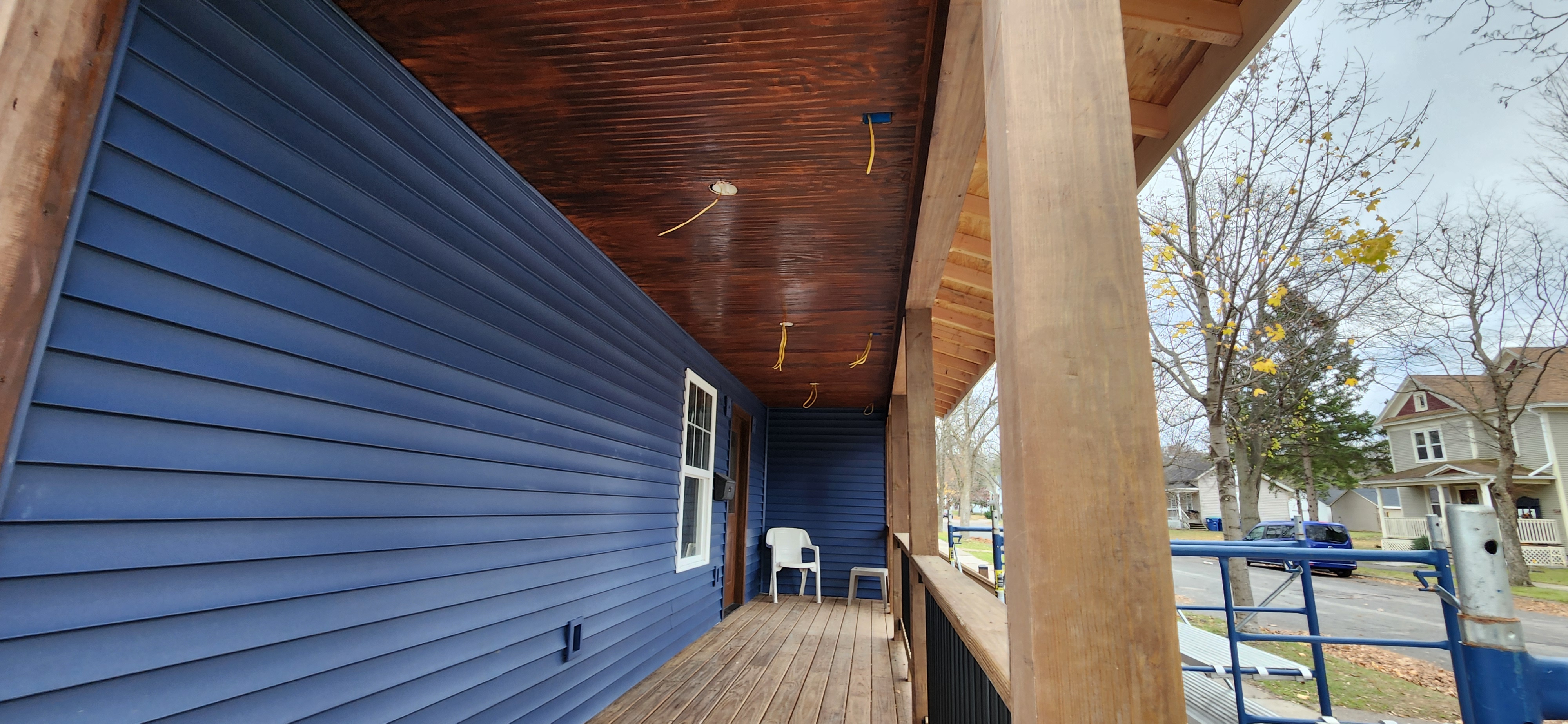 Completed porch ceiling with stained tongue-and-groove boards and new blue siding