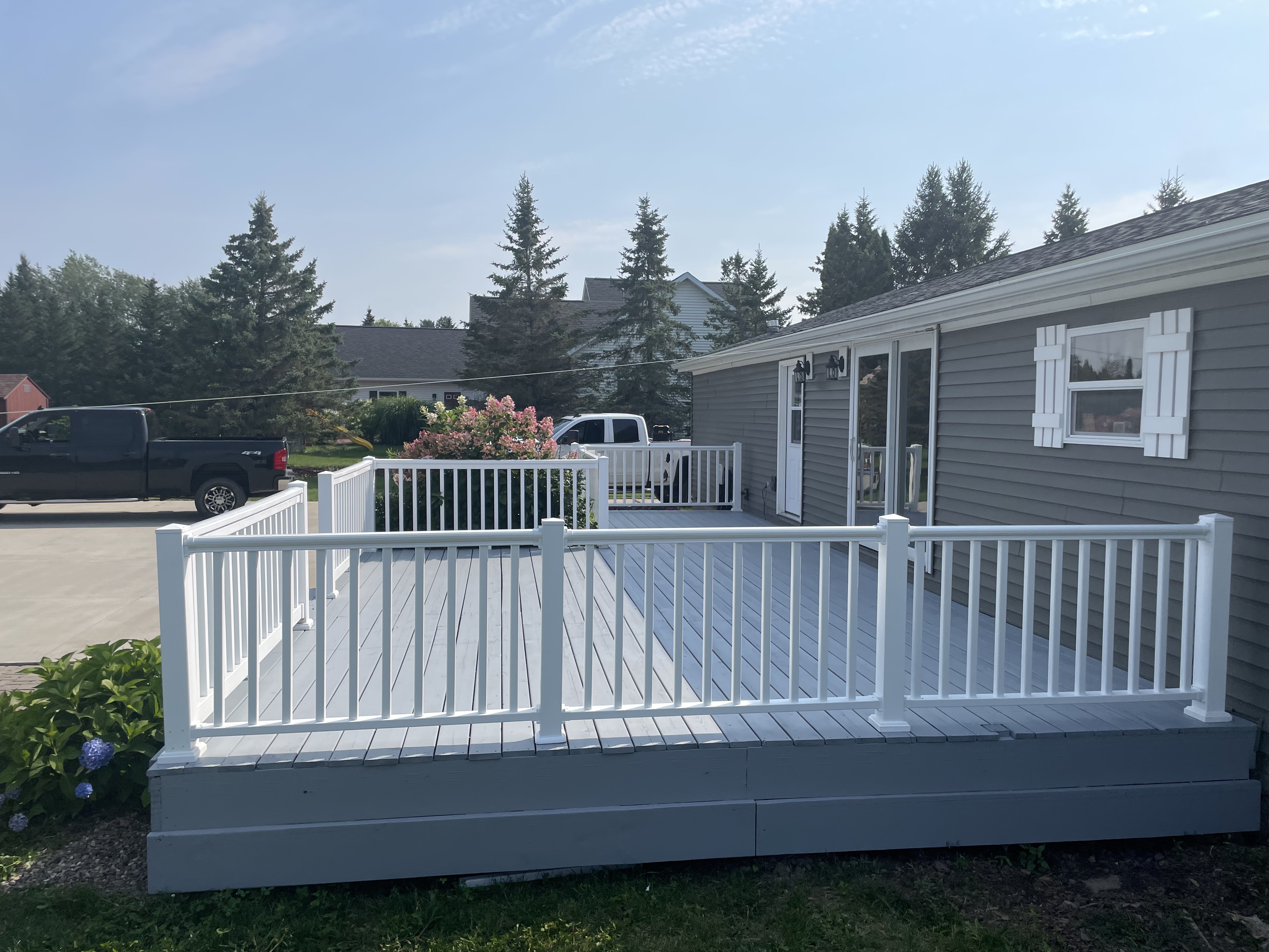 Completed deck with new white vinyl railing and freshly refinished gray deck surface